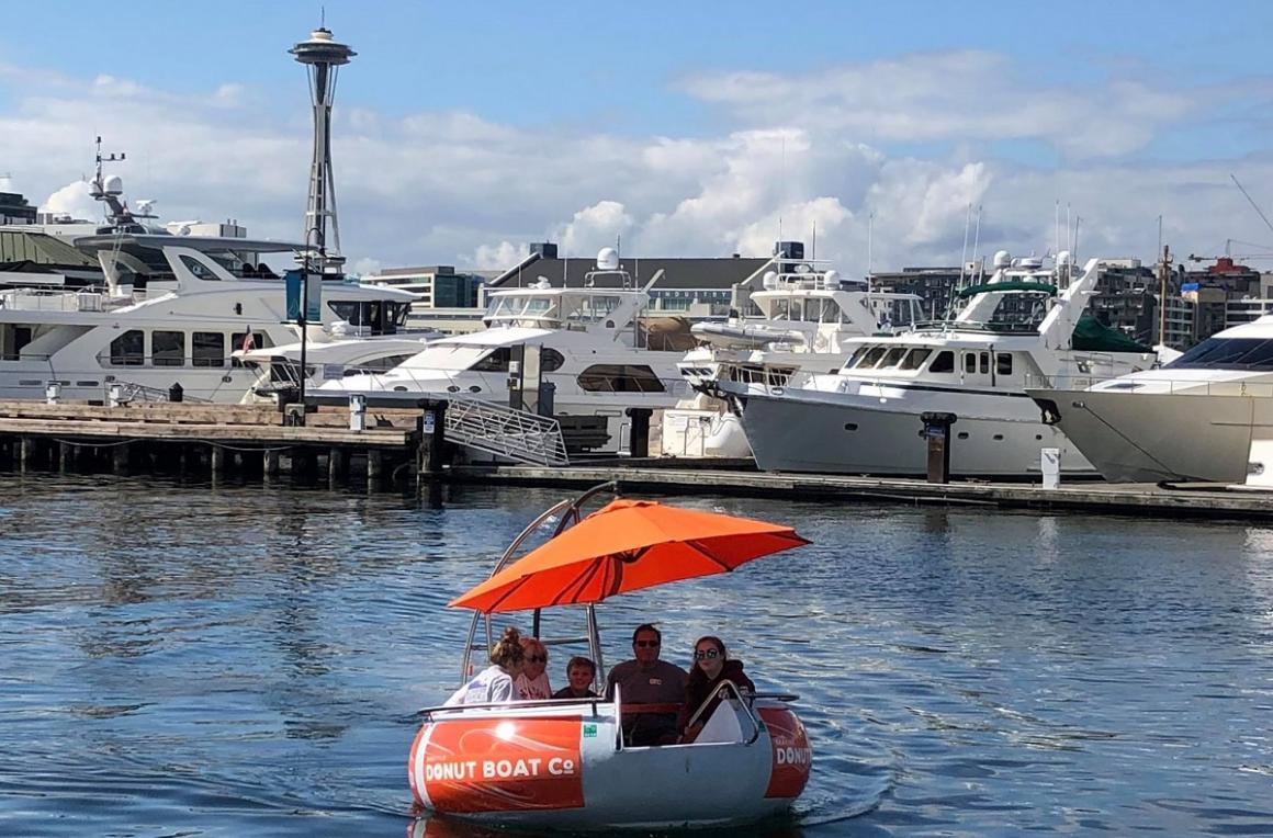 Family riding in a Seattle Donut Boat on Lake Union with Space Needle and MOHAI in the background best summer activities Seattle families tourists
